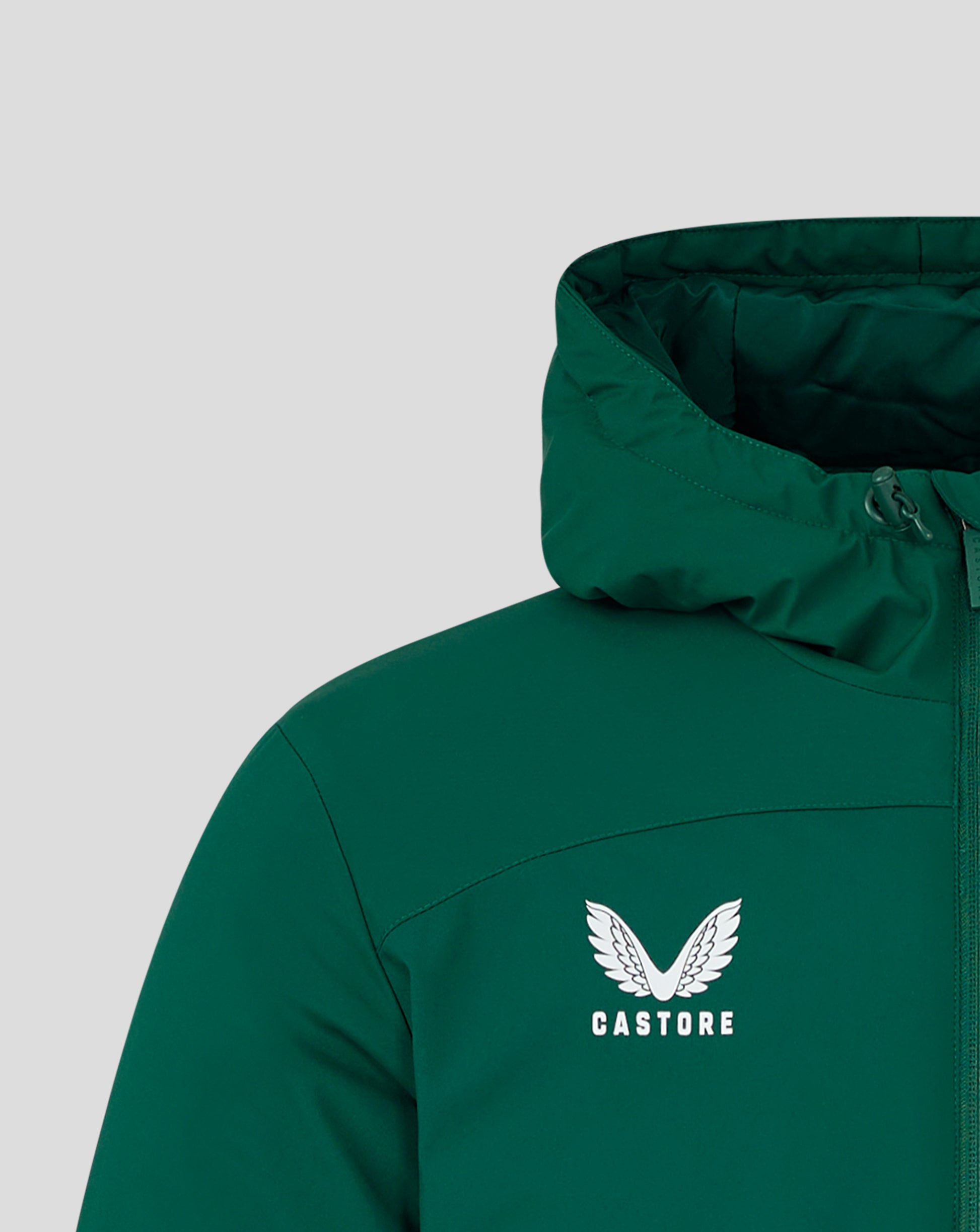 Close-up of green hooded bench jacket showing the Castore logo and wing emblem on the chest