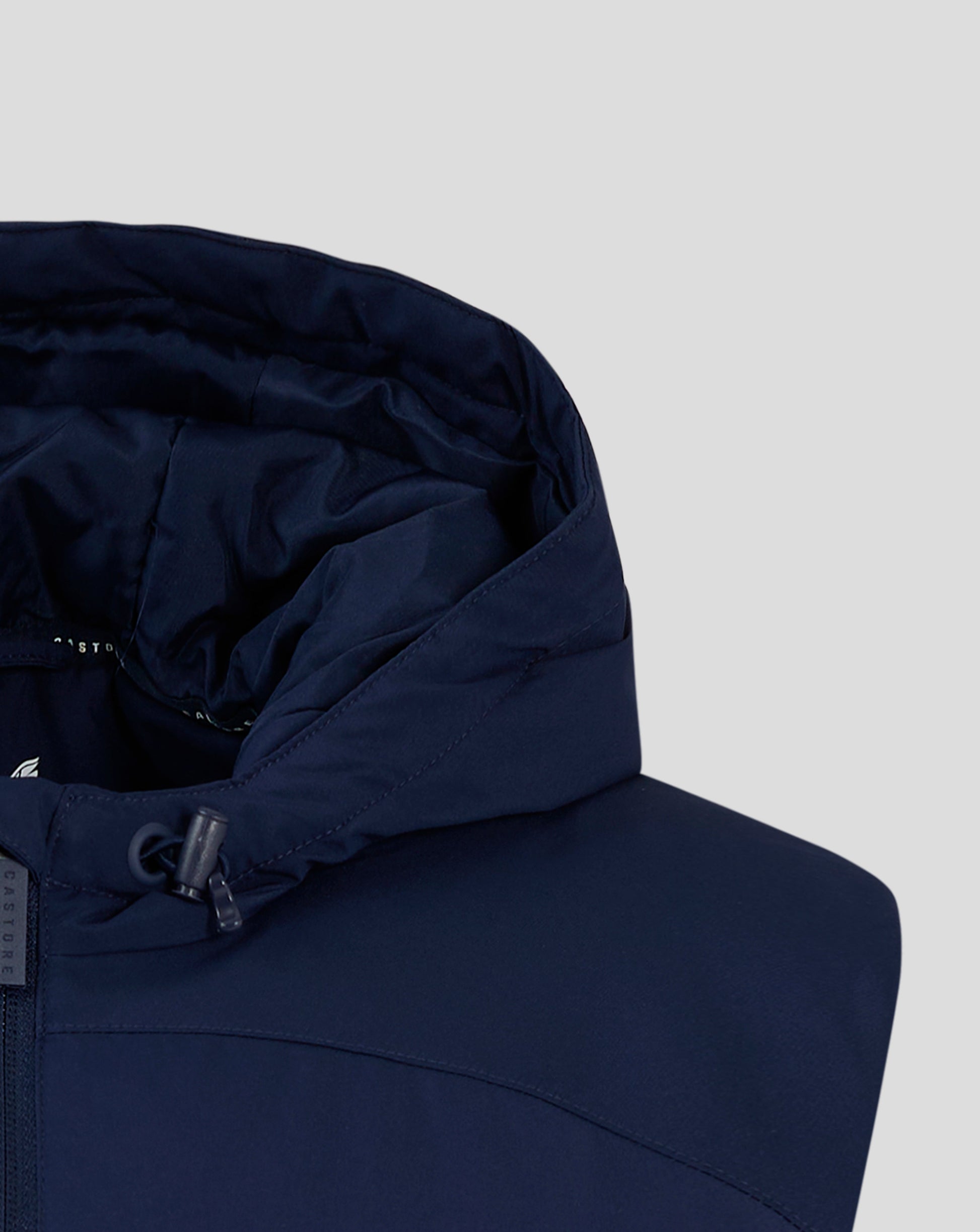 Close up of navy padded gilet hood edge with drawcord toggle and Castore branding.