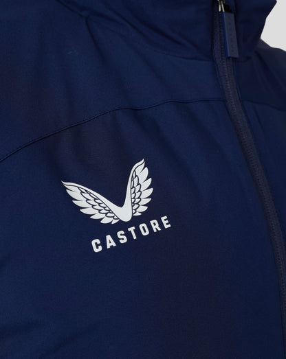 Close-up of navy padded gilet with Castore logo and white wing emblem, featuring the zipper and textured fabric