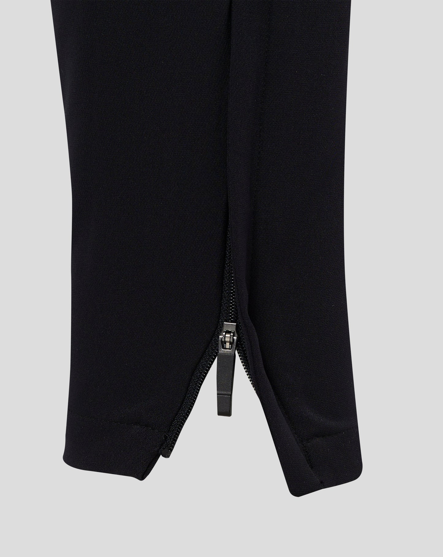 Rear view of black track pants with central seam and tapered legs