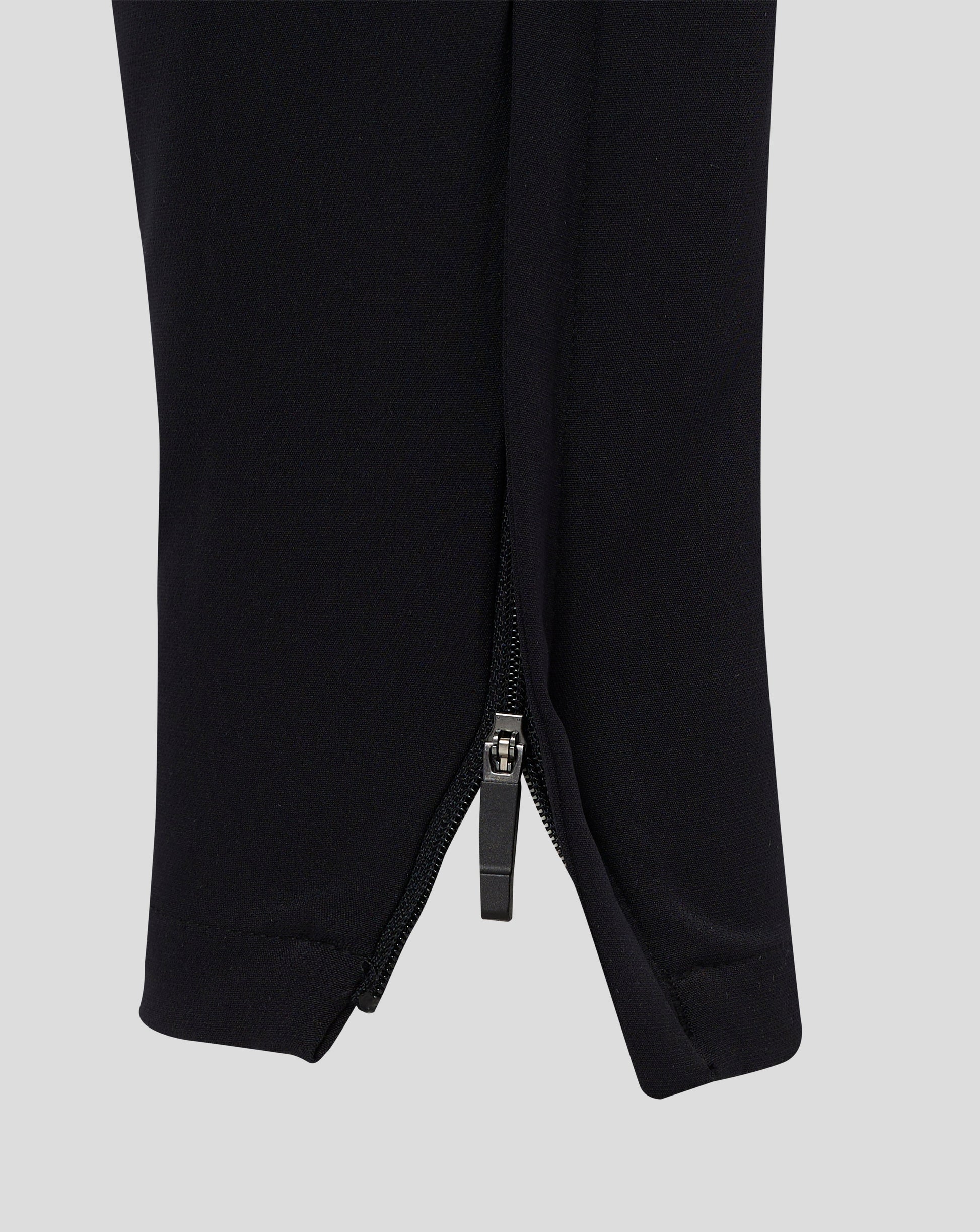 Rear view of black track pants with central seam and tapered legs