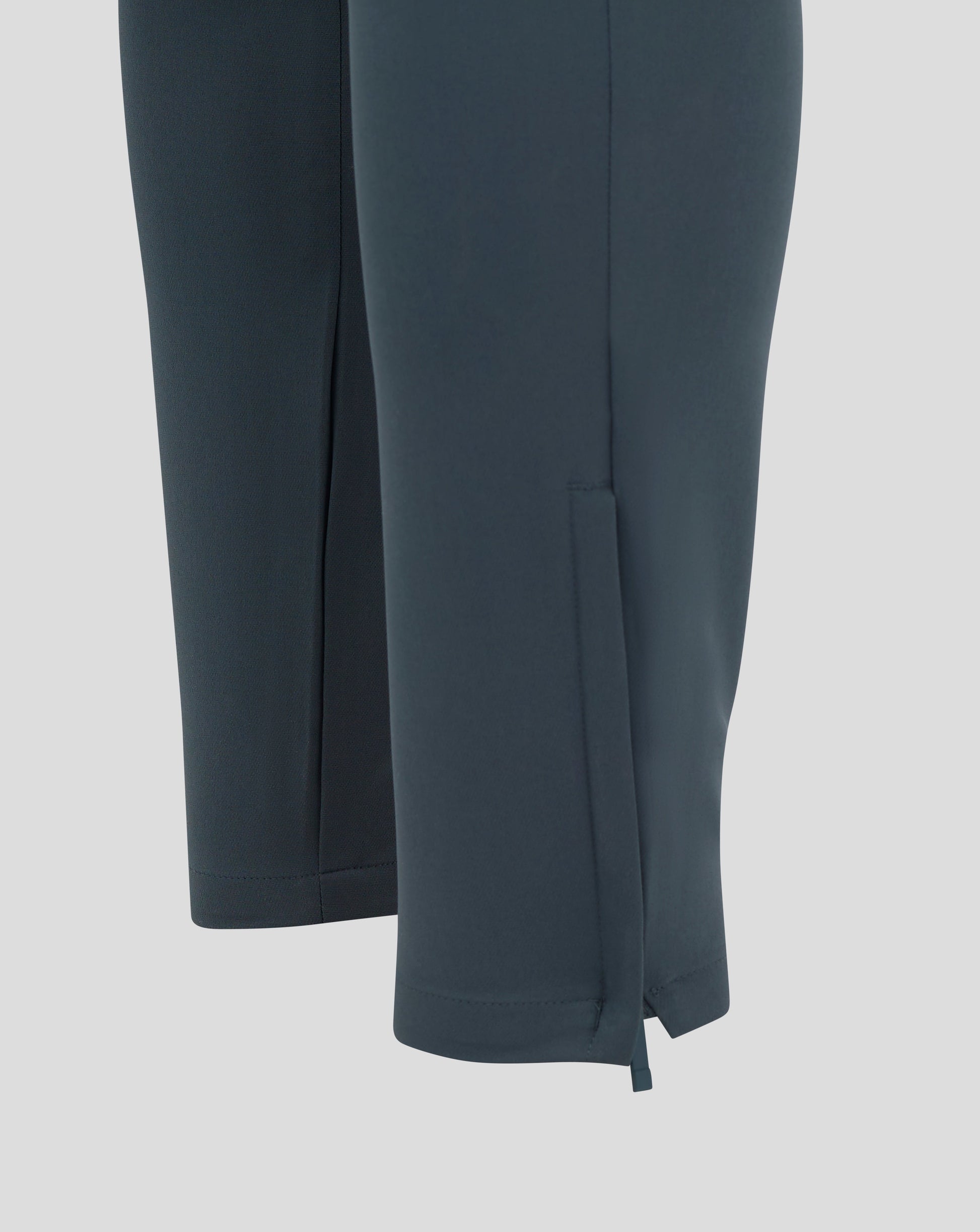 Side view of dark slate track pant leg with a Castore wing logo near the lower thigh