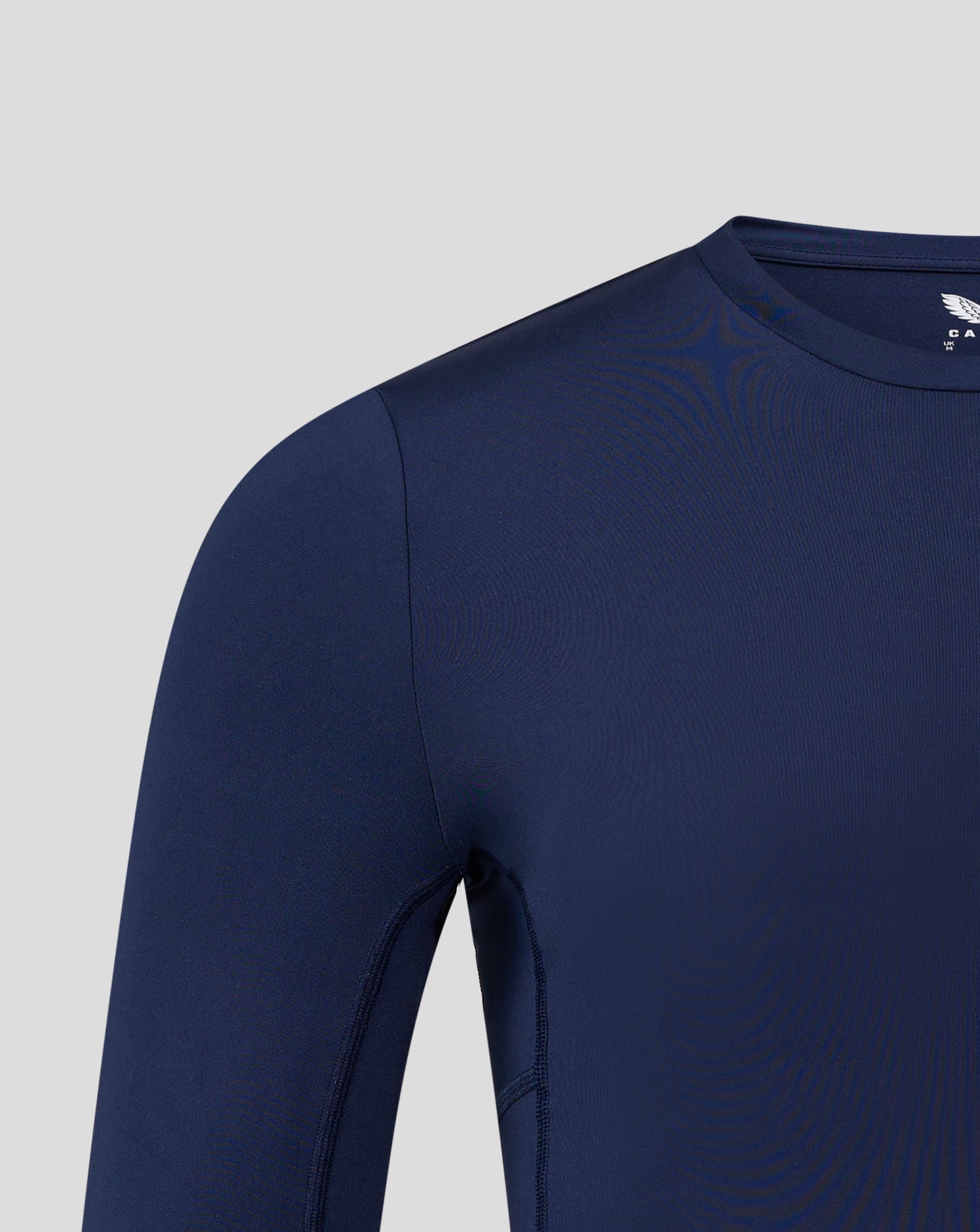 Navy long sleeve baselayer top angled view showing crew neck collar shoulder seam and subtle Castore branding