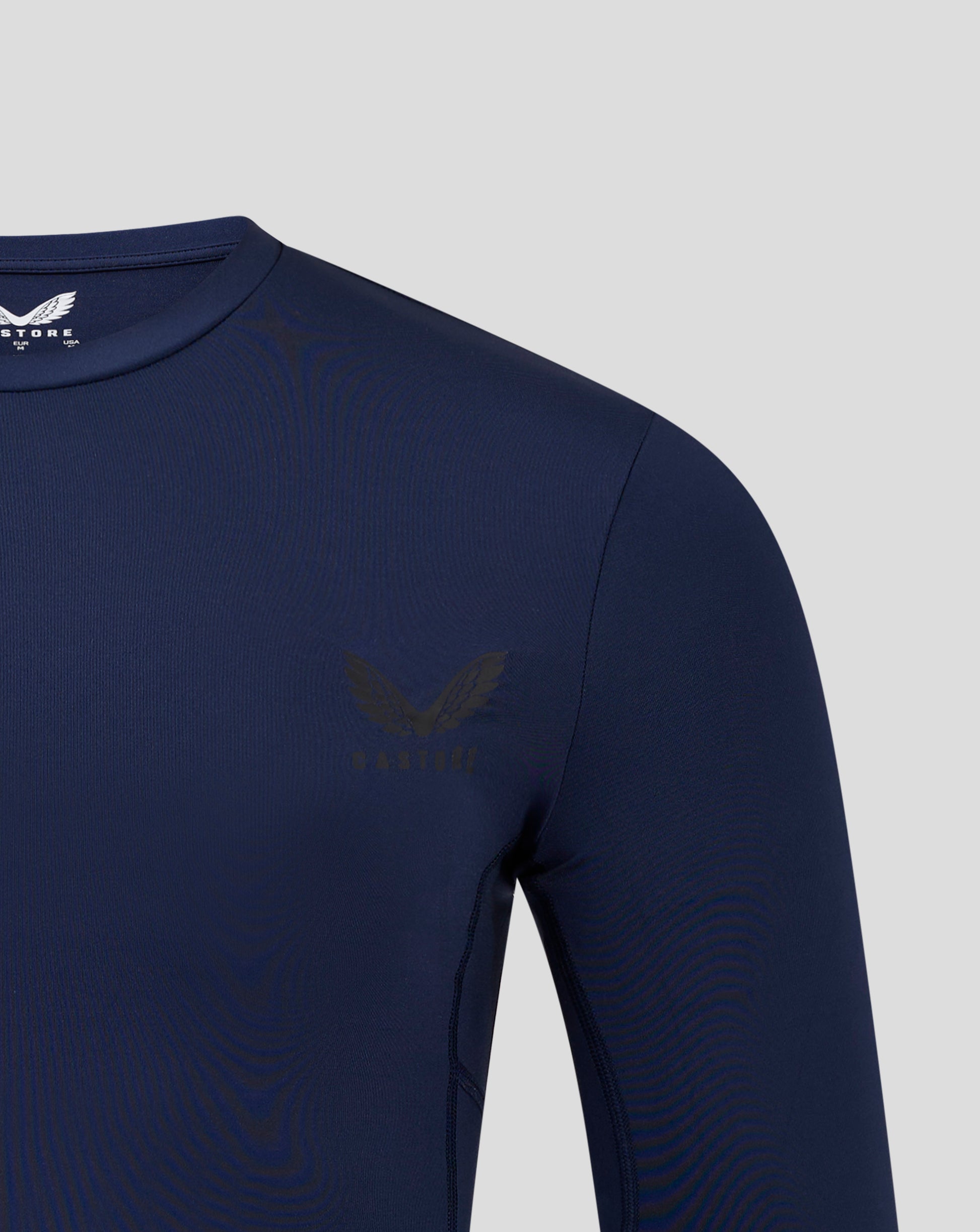 Navy mens Baselayer Long Sleeve Top close up of shoulder and chest with crew neck collar and visible side panels and heat sealed Castore logo