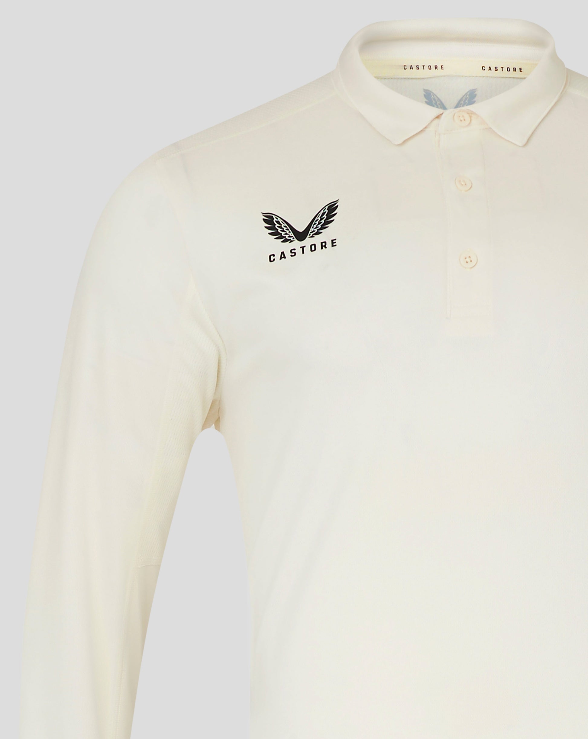 Torso view of Cannoli Cream cricket shirt showing left chest Castore wing logo and pale button placket