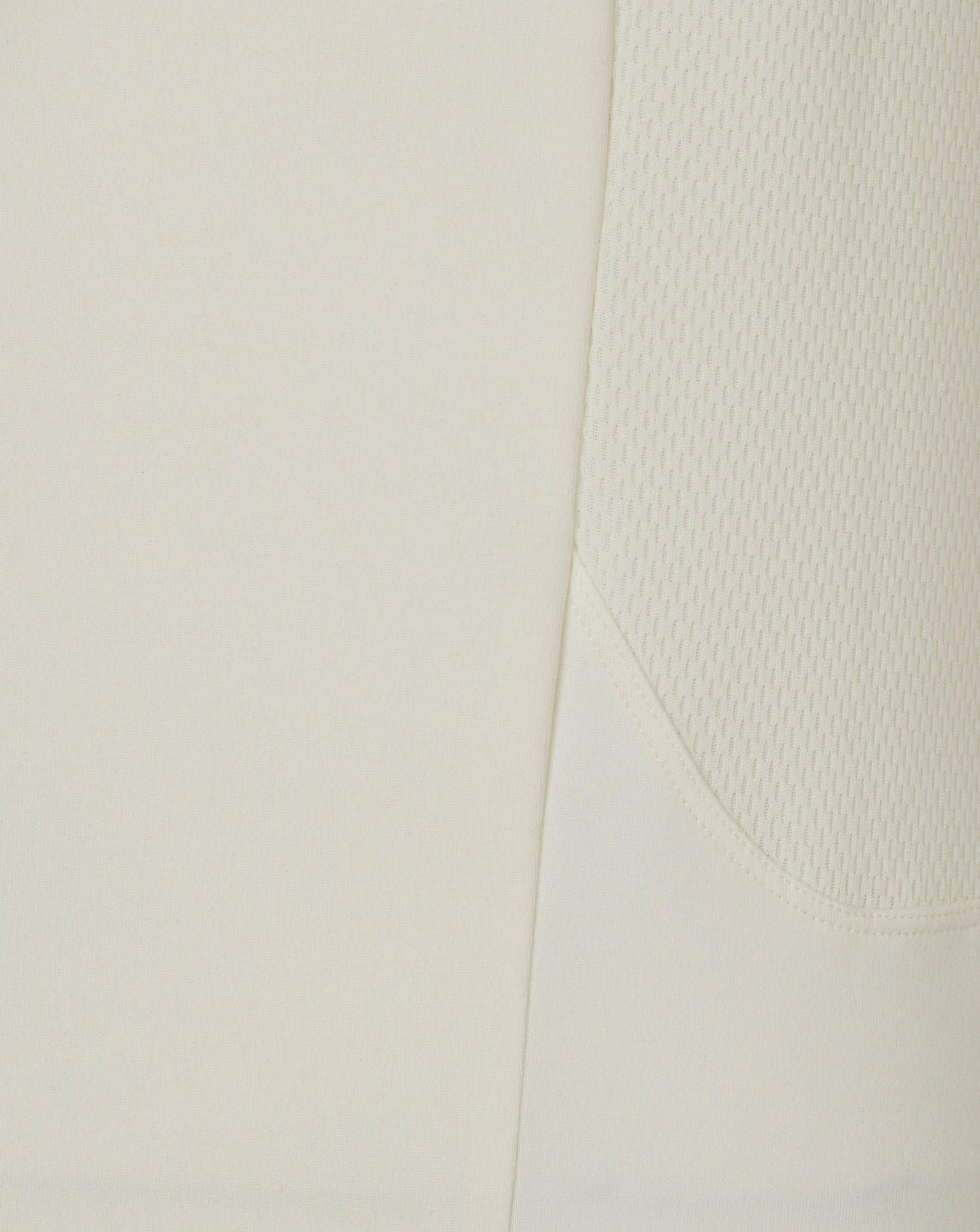 Close-up of Cannoli Cream men's cricket jumper fabric showing a diagonal seam and side mesh panel.