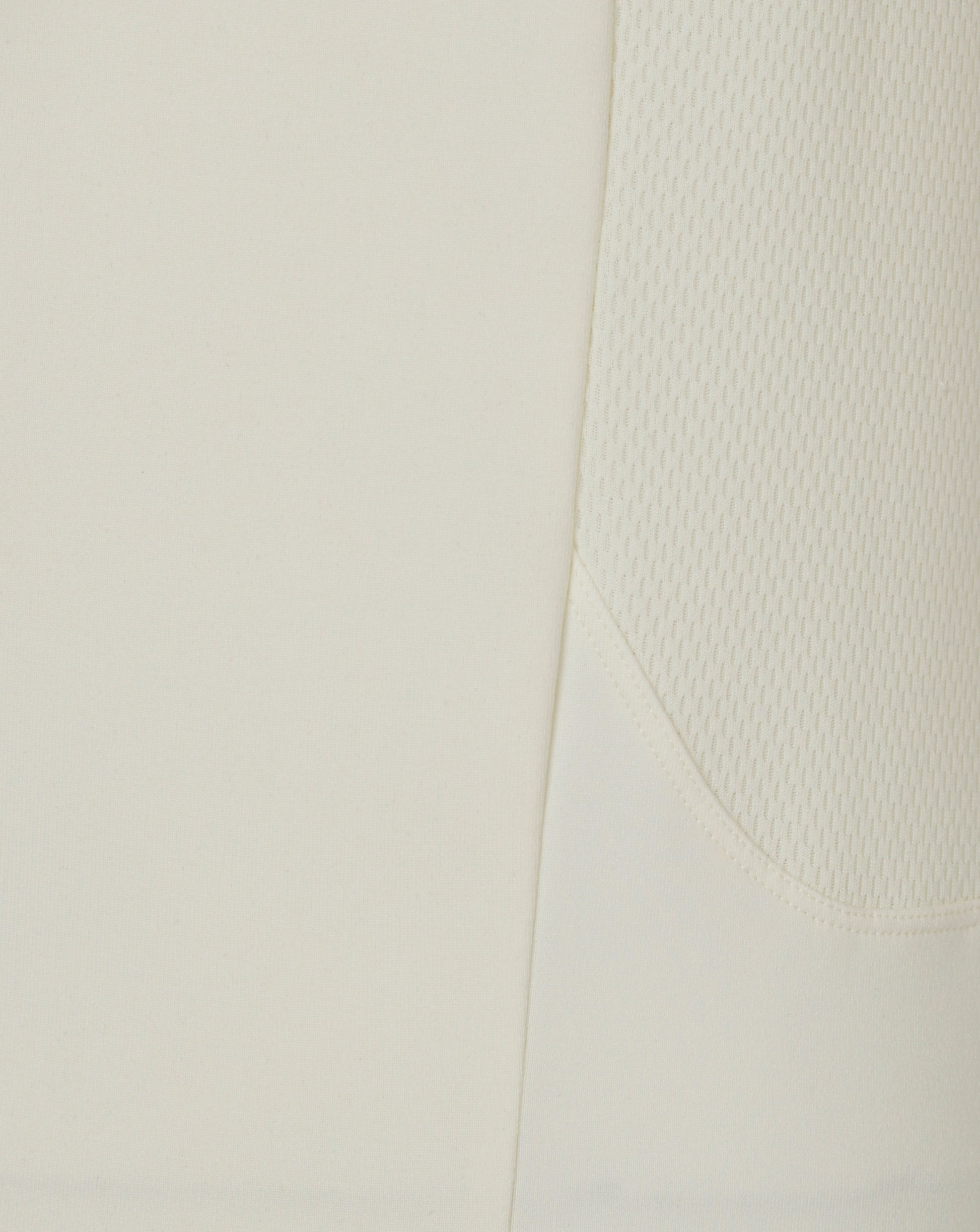 Close-up of Cannoli Cream men's cricket jumper fabric showing a diagonal seam and side mesh panel.
