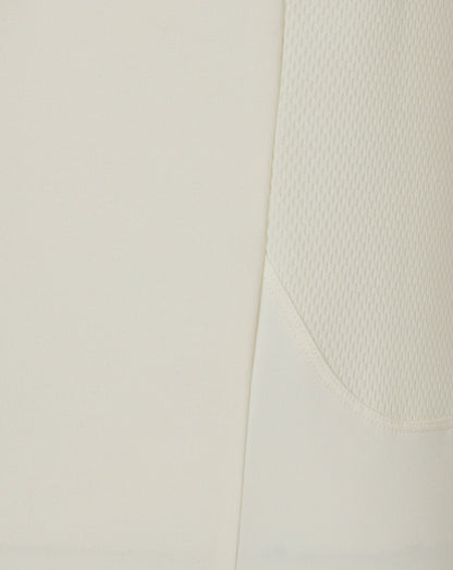 Close-up of Cannoli Cream men's cricket jumper fabric showing a diagonal seam and side mesh panel.