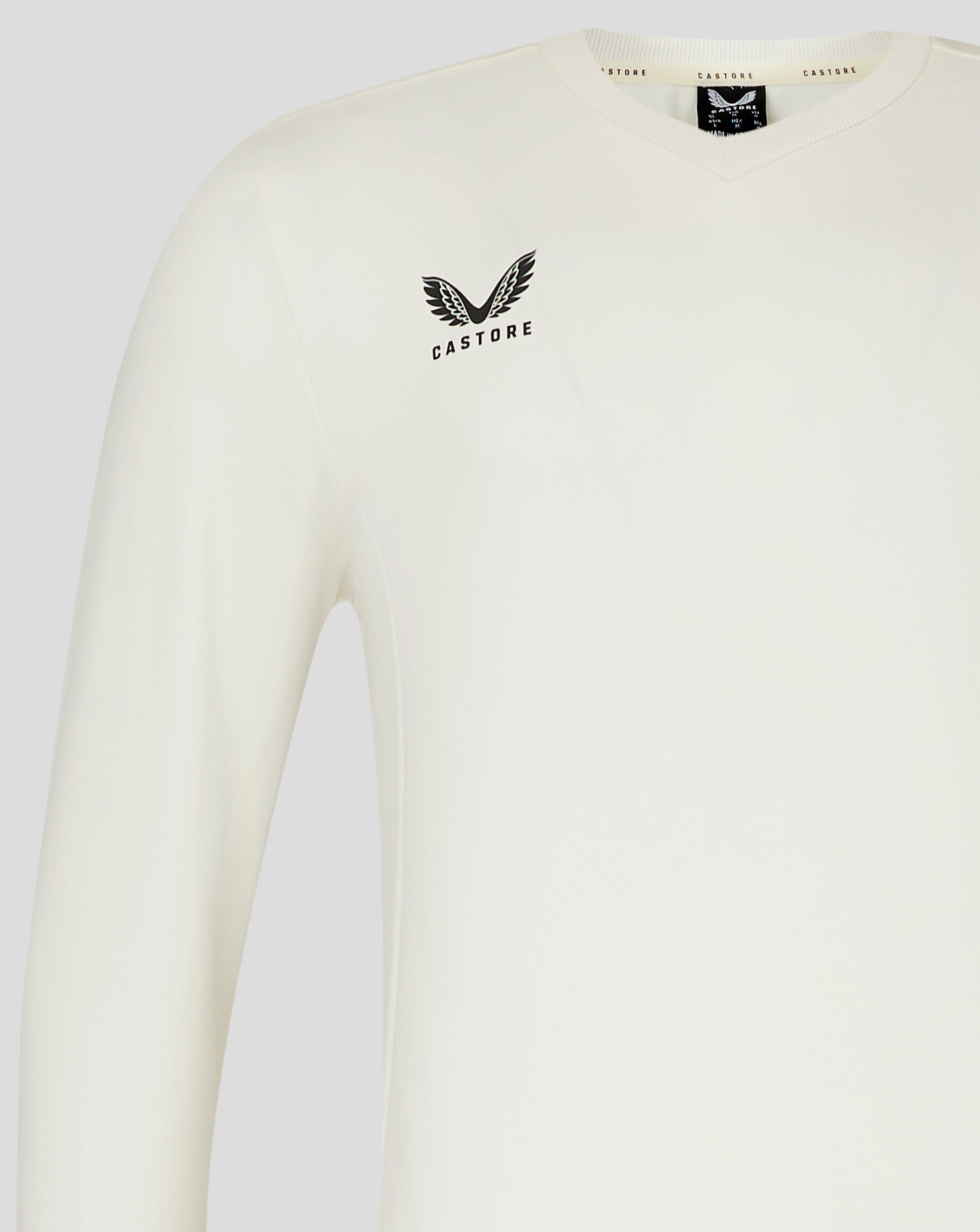 Left chest view of Cannoli Cream cricket jumper with Castore logo and neck label visible.