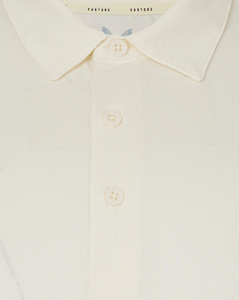 Close up of cream cricket polo collar with three buttons and Castore label at the neckline.