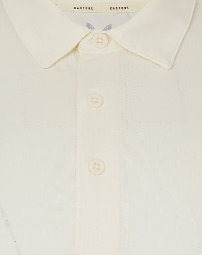 Close up of cream cricket polo collar with three buttons and Castore label at the neckline.