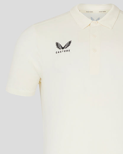 Front view of cream cricket polo showing Castore logo on the left chest and clean polo silhouette.