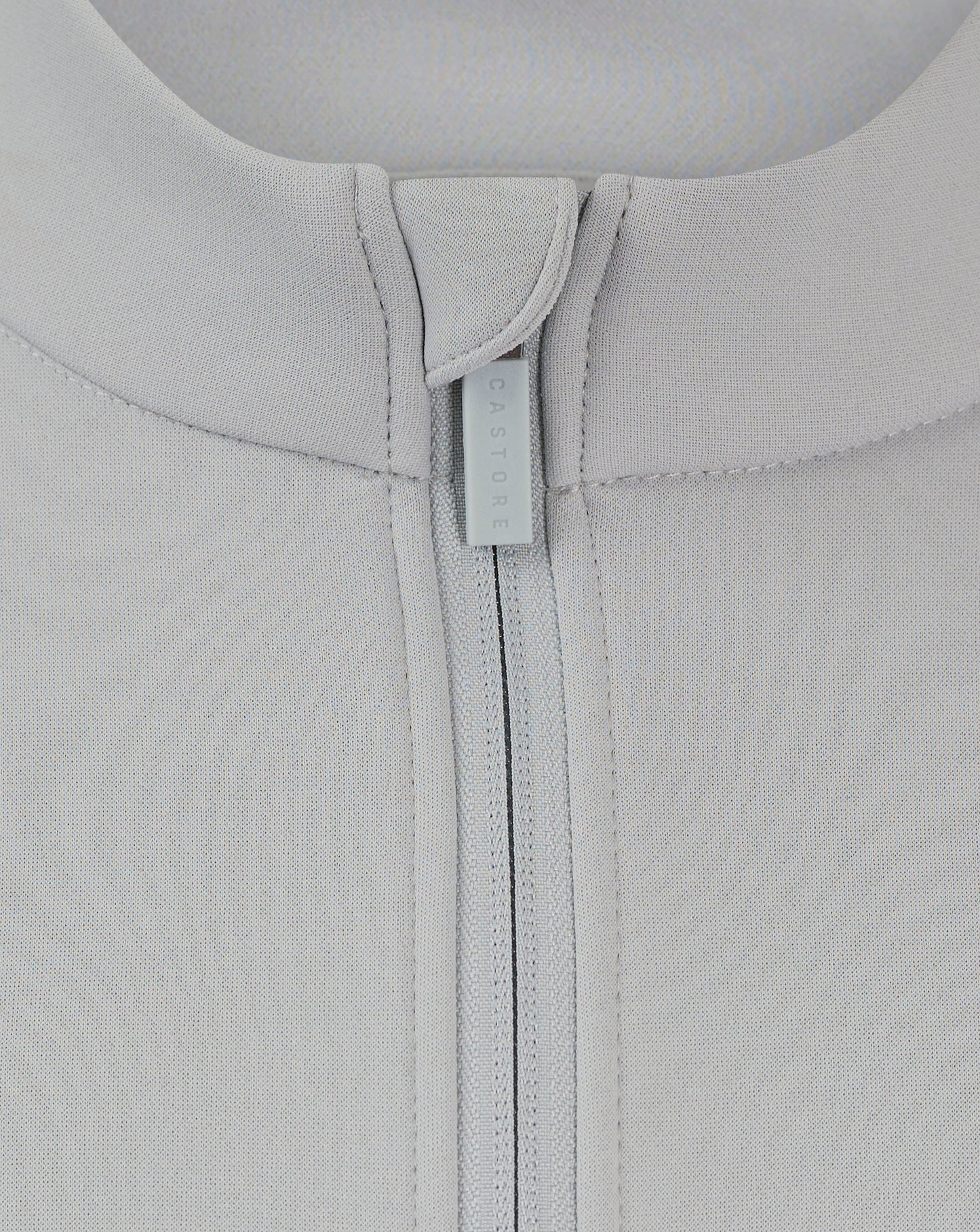 Close-up of back neck area showing Castore branded zipper pull on a light gray fleece jacket