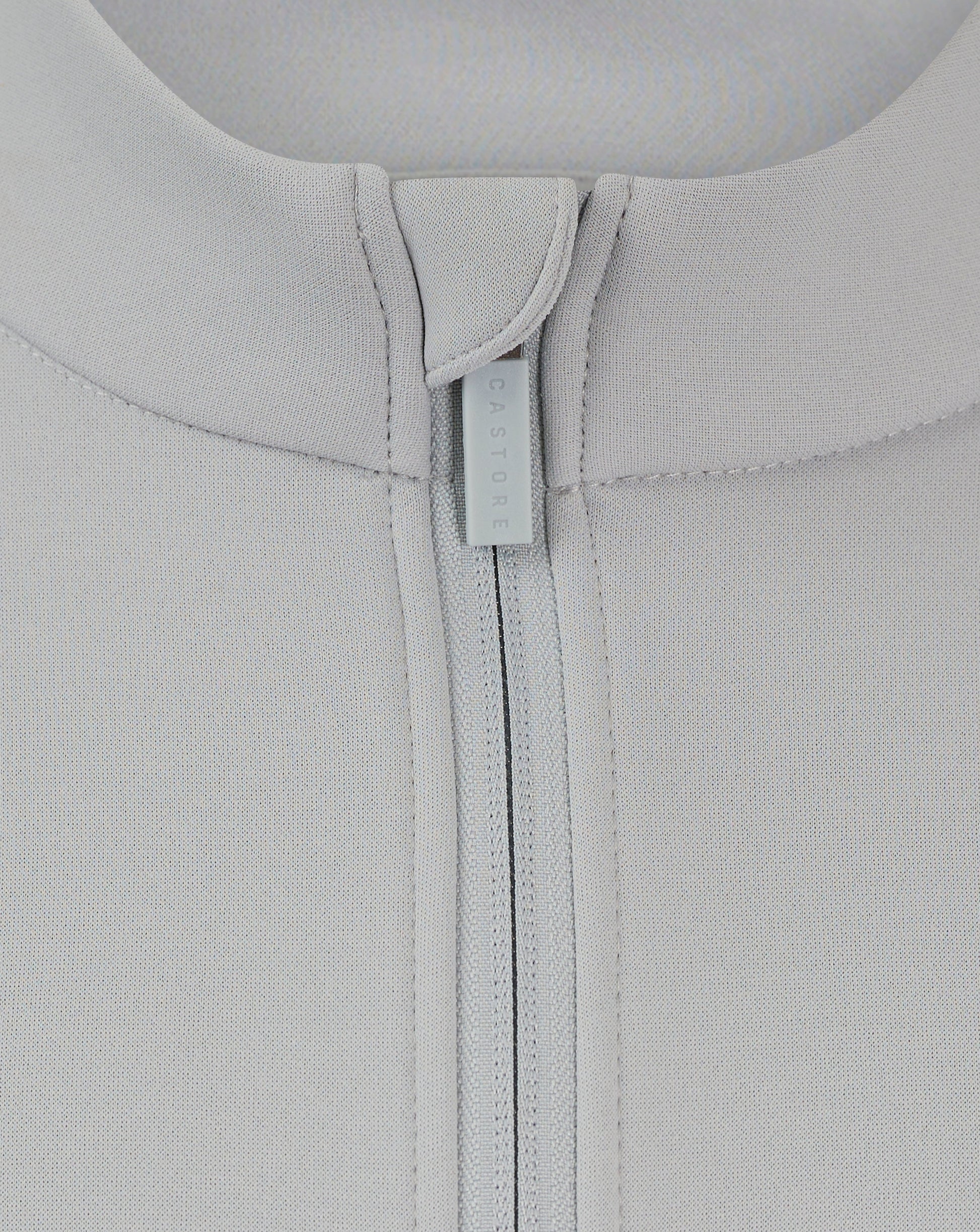 Close-up of back neck area showing Castore branded zipper pull on a light gray fleece jacket