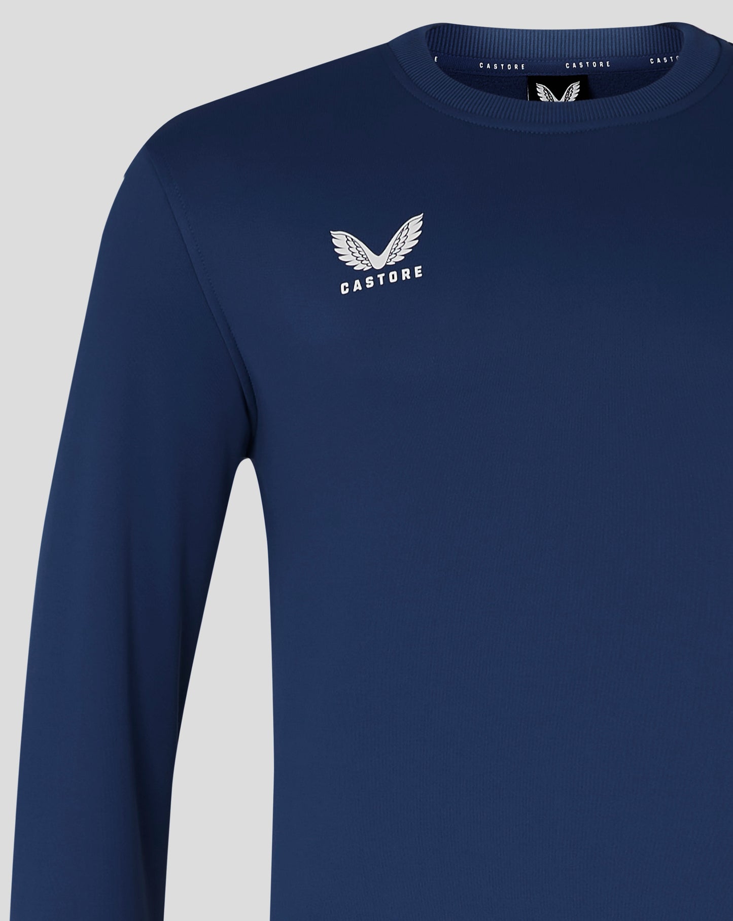Close up of navy brushback sweatshirt displaying a white wing logo and CASTORE text on the left chest