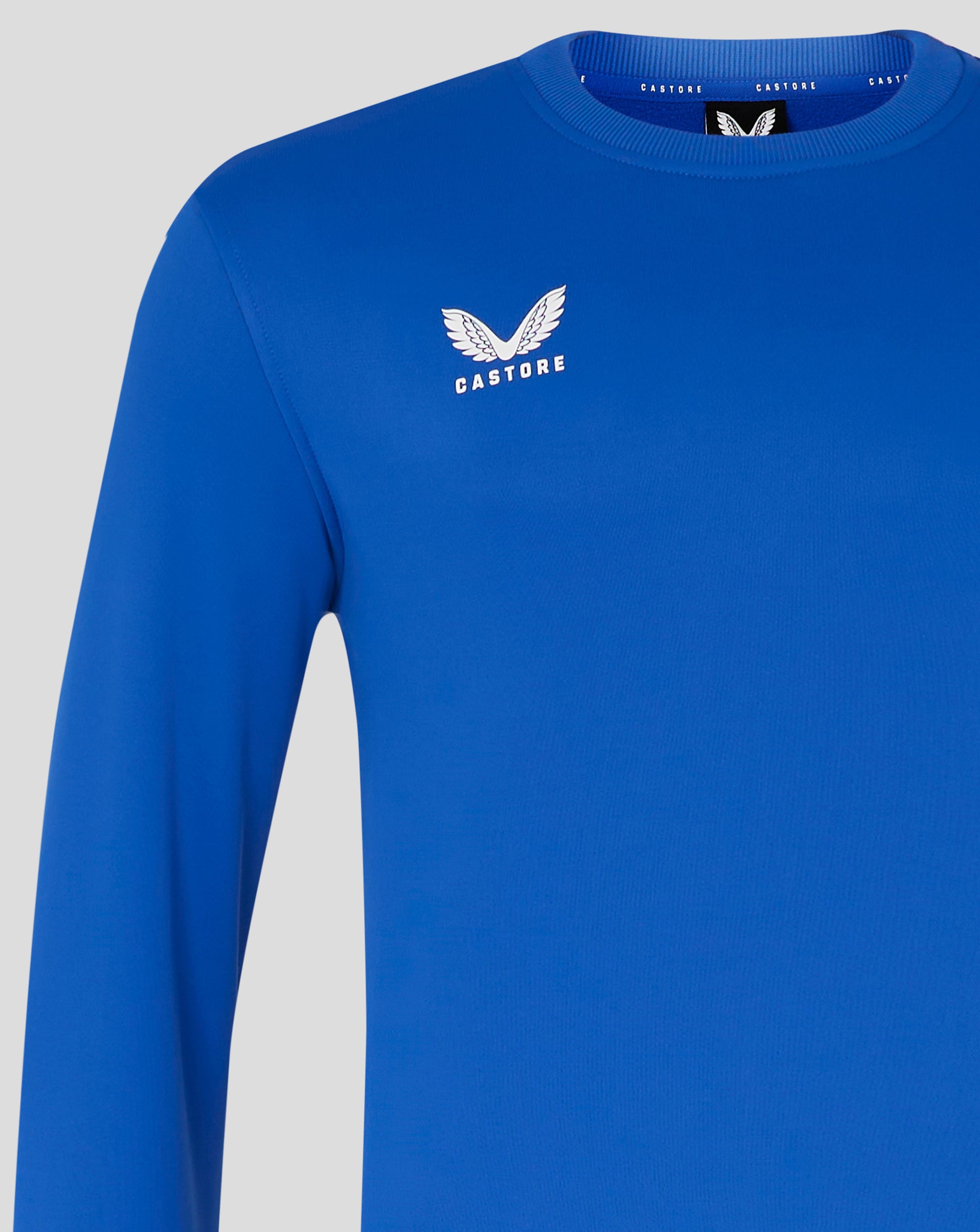 Close-up of blue sweatshirt chest showing white Castore wing logo on the left side