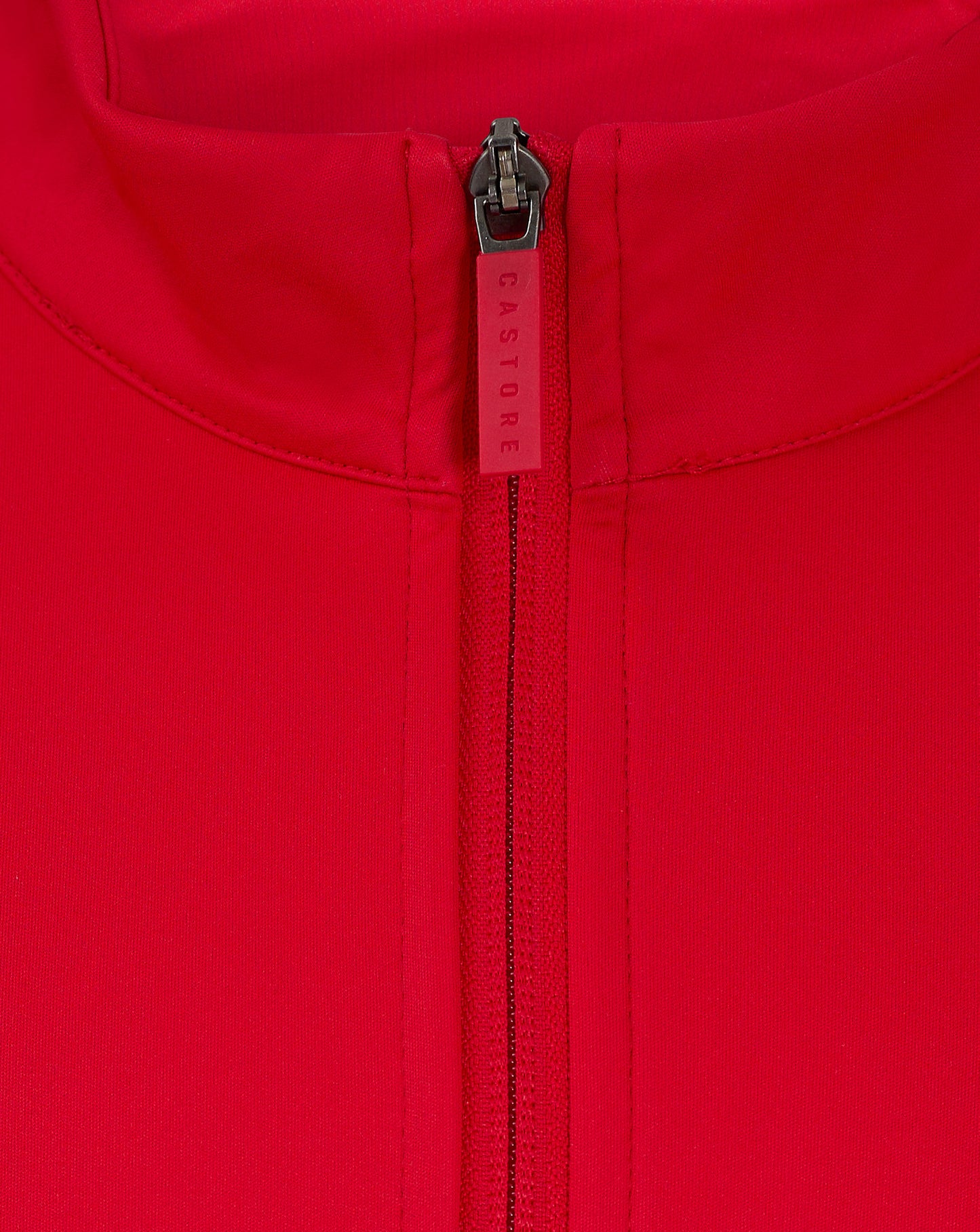 Close up of a red jacket zipper at the collar with Castore branding on the zipper pull