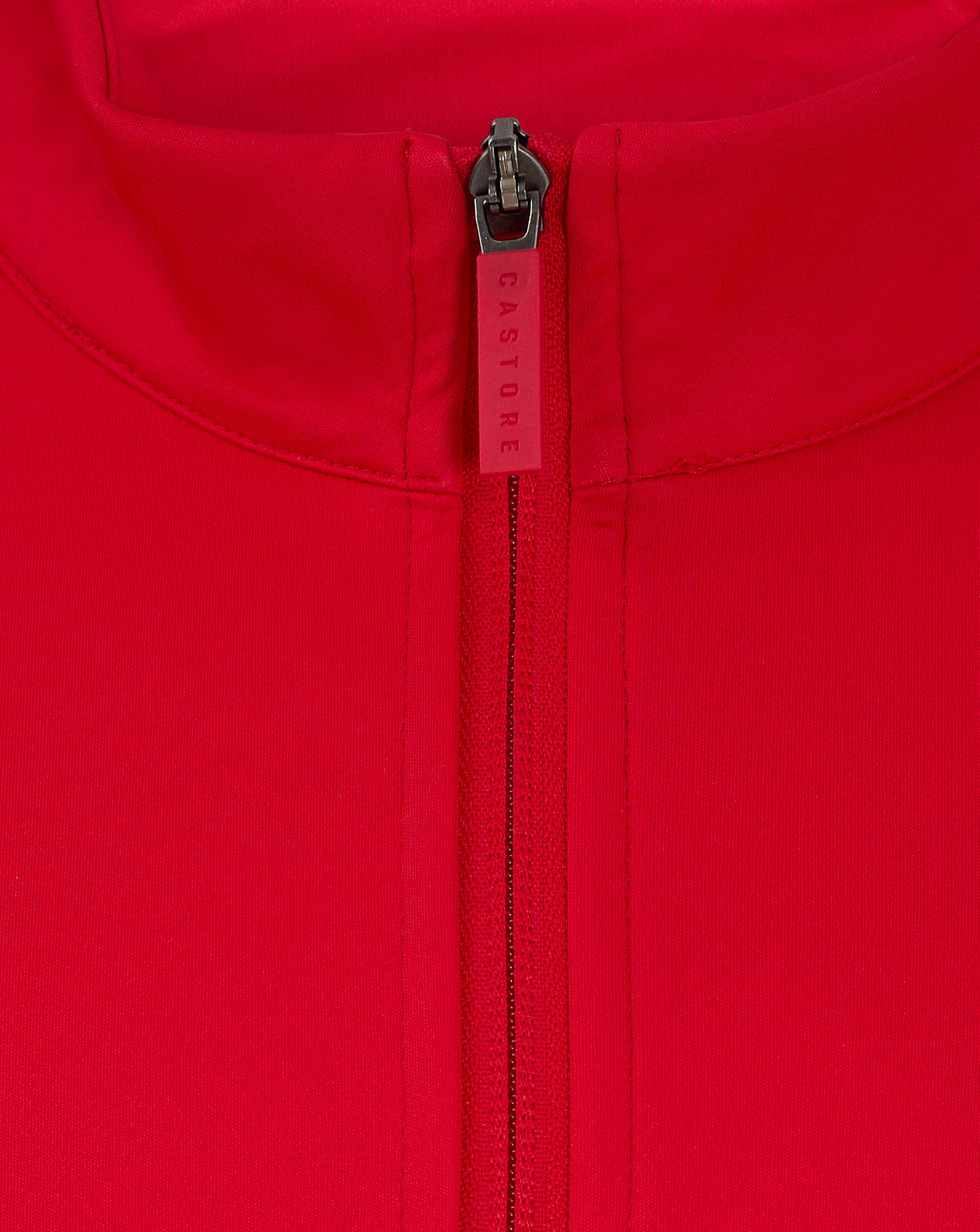 Close up of a red jacket zipper at the collar with Castore branding on the zipper pull