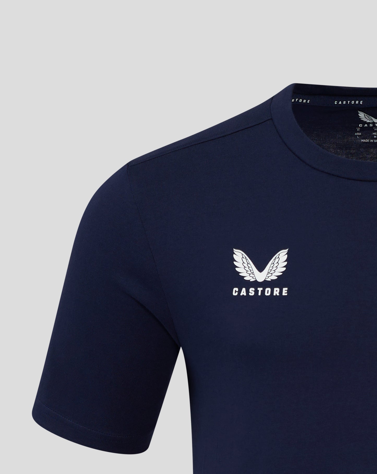 Close up of navy tee showing neck label and white wing Castore logo on chest