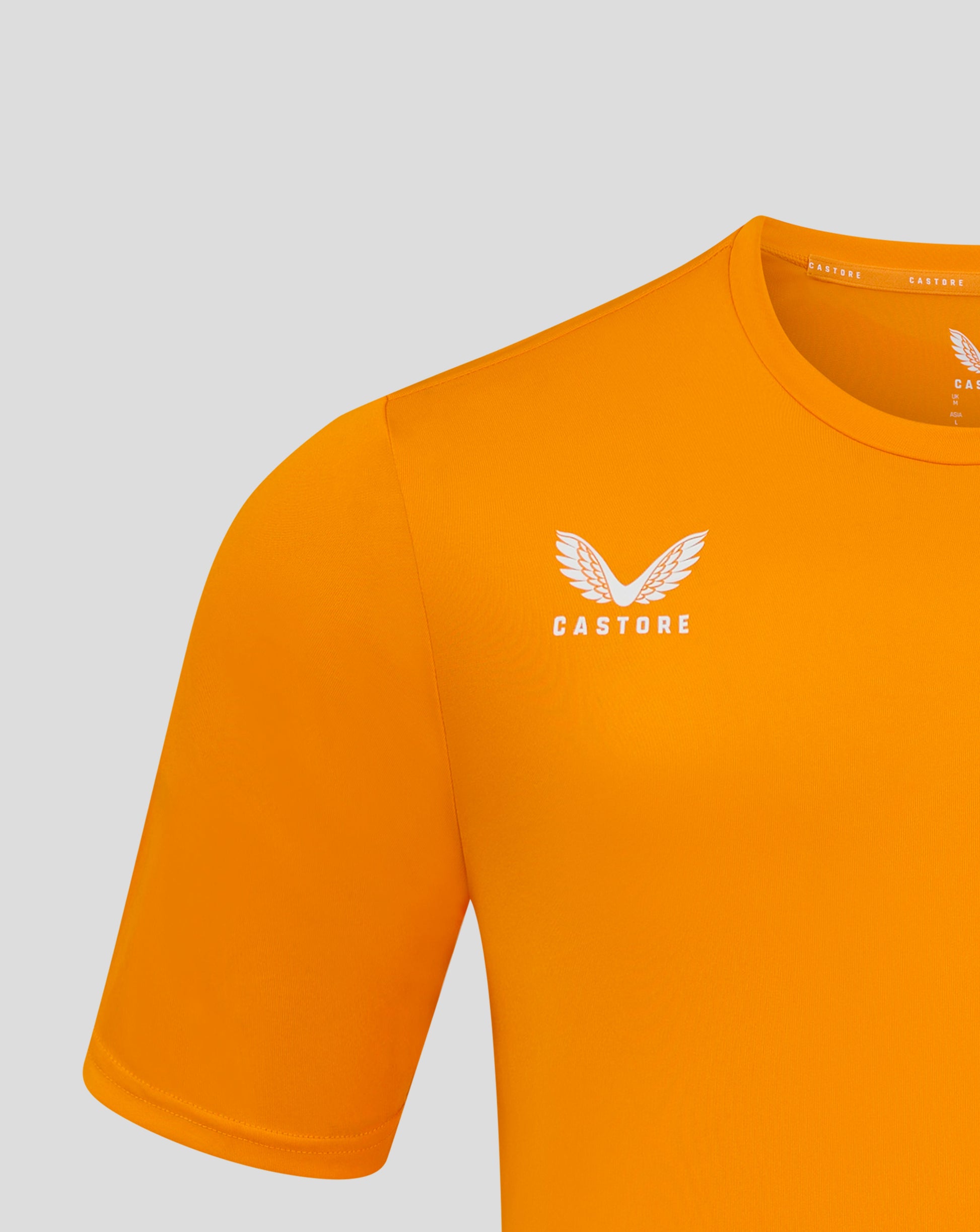 Close up of the orange tee neckline showing the Castore label along the inside and partial wing logo