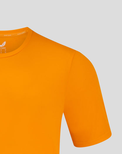Mens performance tee in bright marigold shown close up at the crew neck with shoulder seam and heat sealed Castore logo