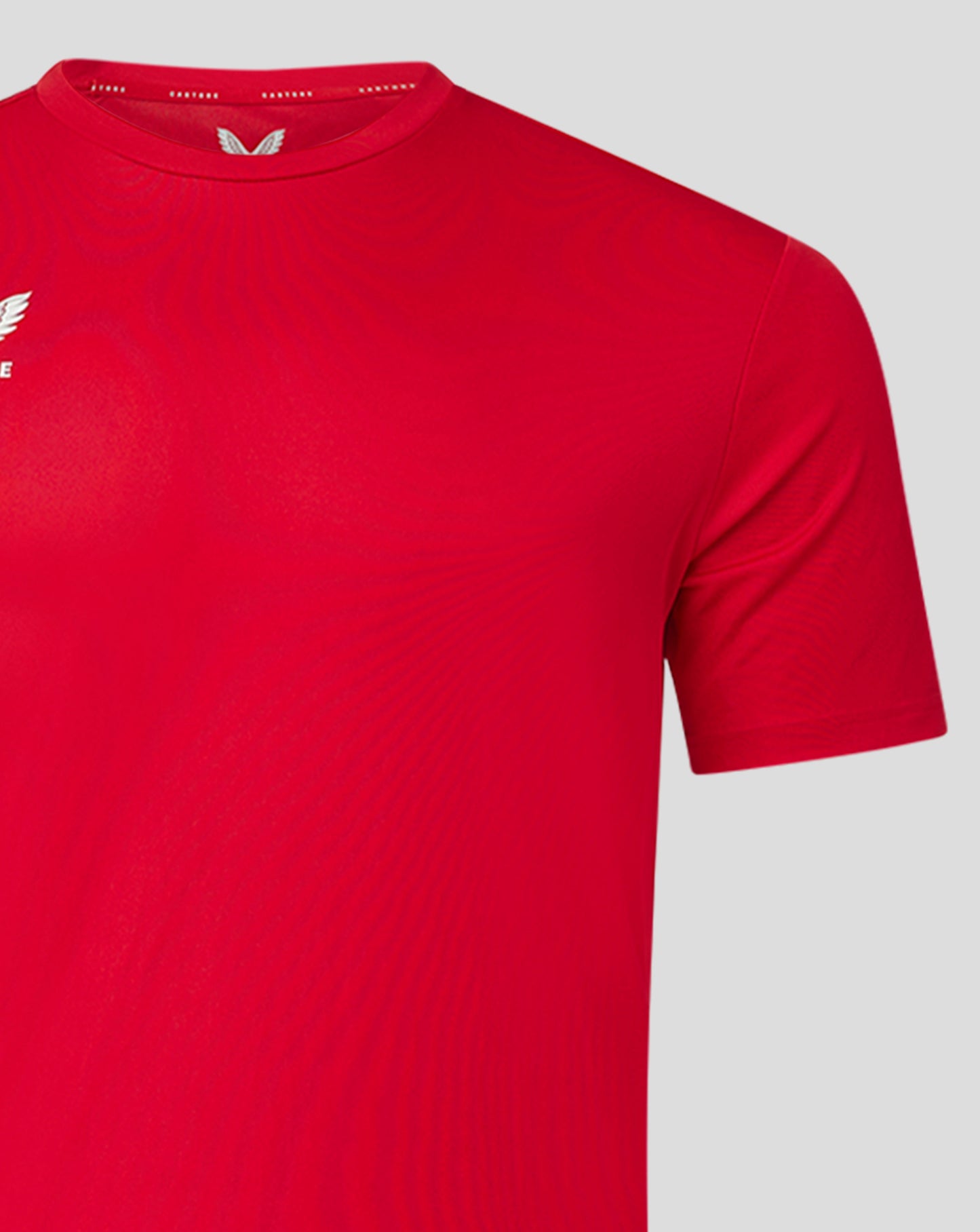 Close-up of red men's performance tee with crew neck and heat sealed Castore logo on the chest