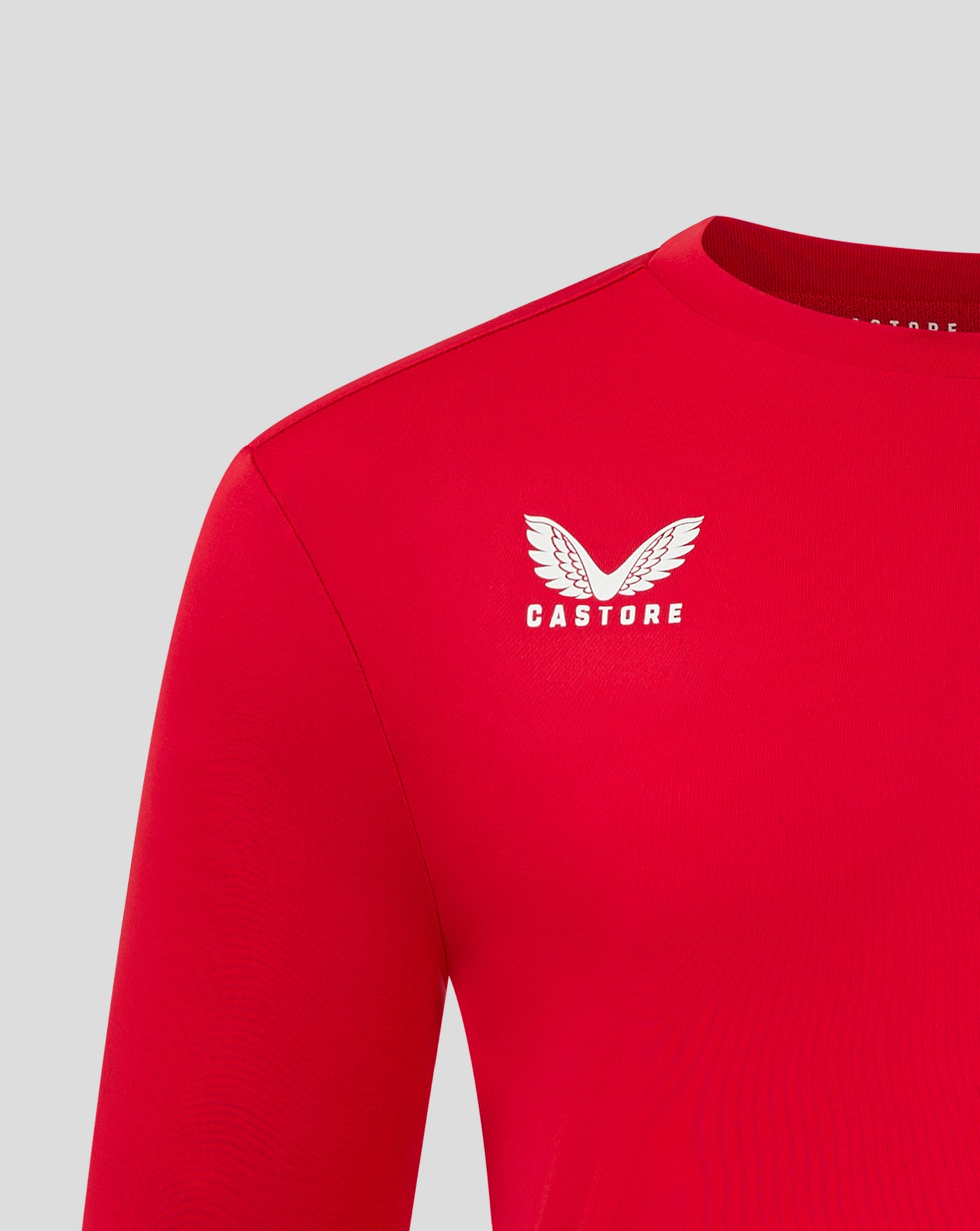 Close up of red Castore tee chest showing white wing logo and CASTORE text