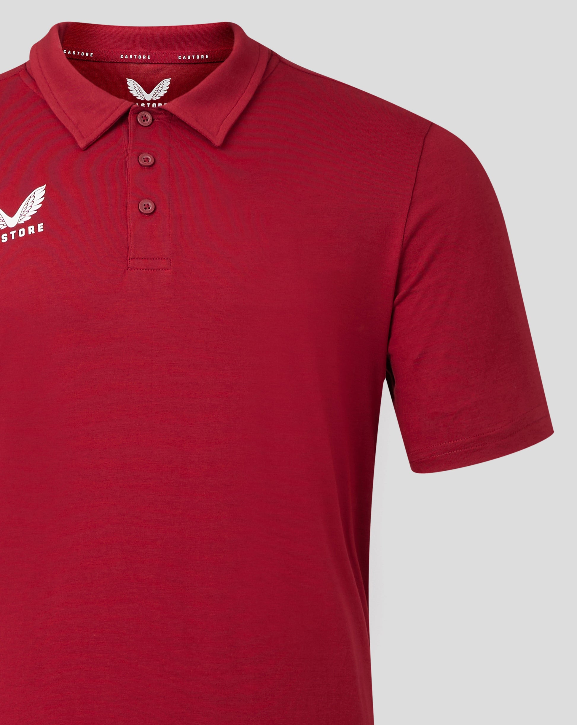 Red polo with collar and three button placket and Castore logo on the chest.