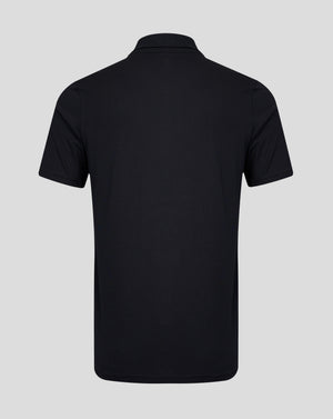 Rear view of a black polo shirt with a simple collar and short sleeves against a light gray background