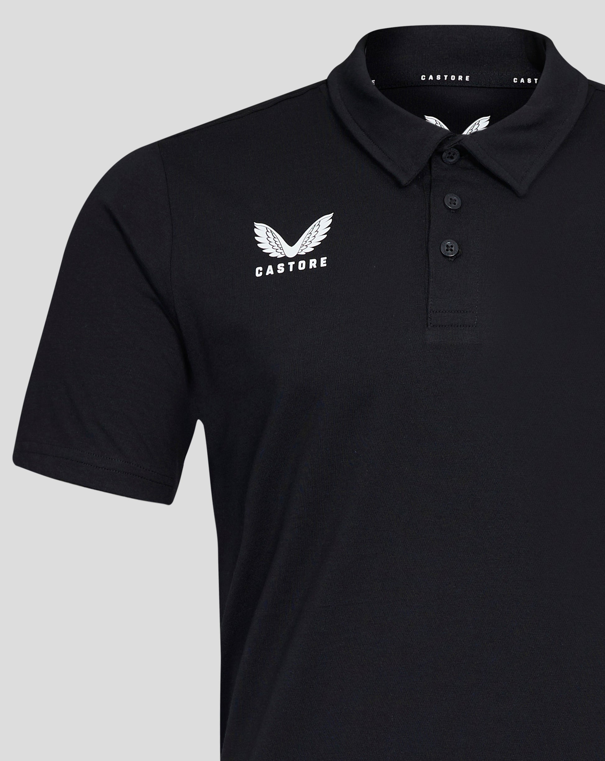 Close-up of the black polo chest showing the white Castore wing logo and the three button placket at the collar