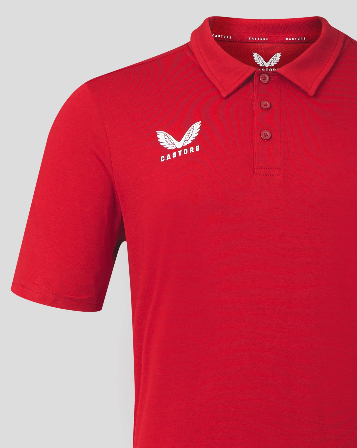 Red Castore polo with white chest logo and wing emblem near collar, features a self fabric collar and three button placket