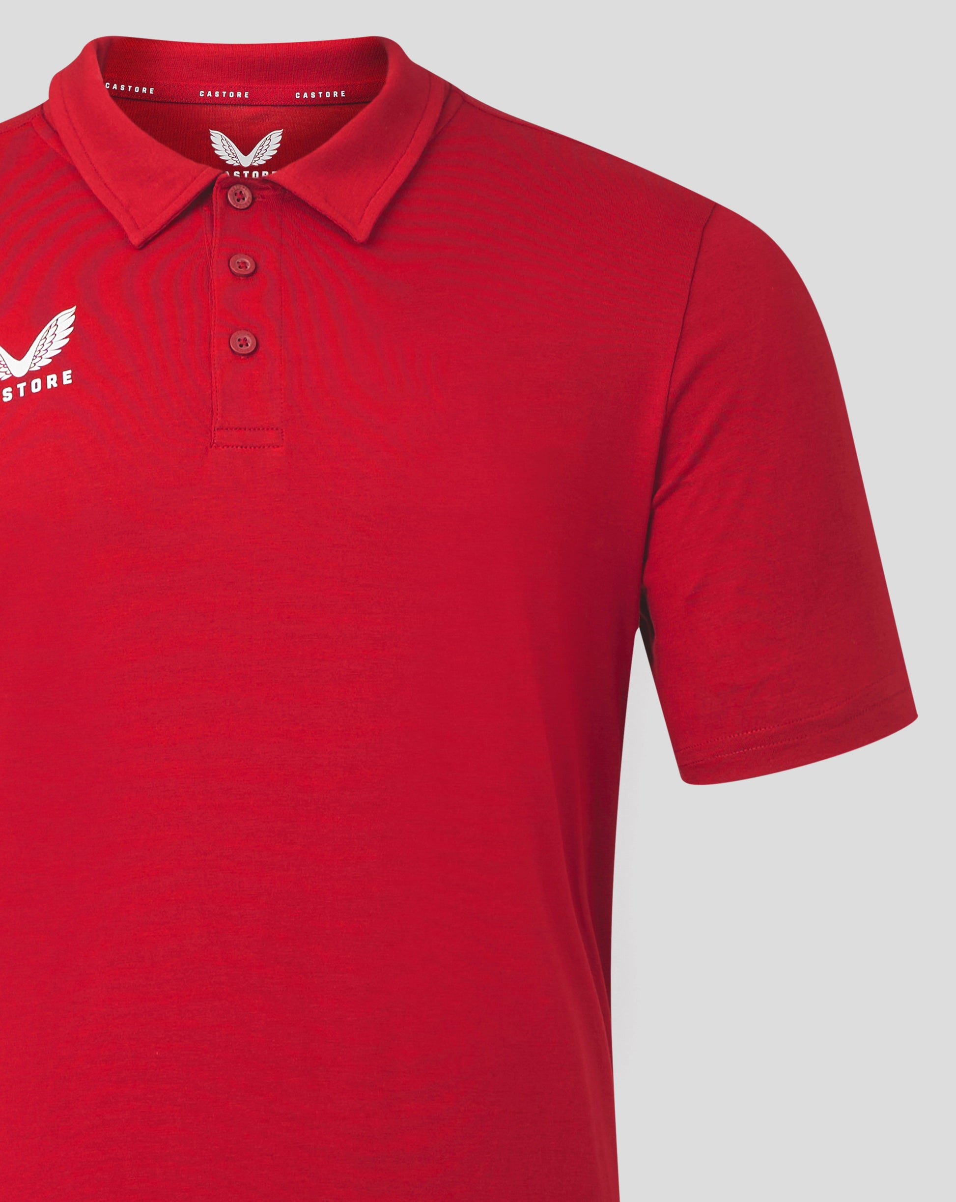 Red polo with small dark Castore crest on the left chest