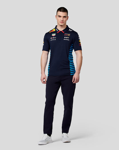 Front view of a male model wearing a night sky navy Red Bull Racing polo with sponsor logos and blue side stripes