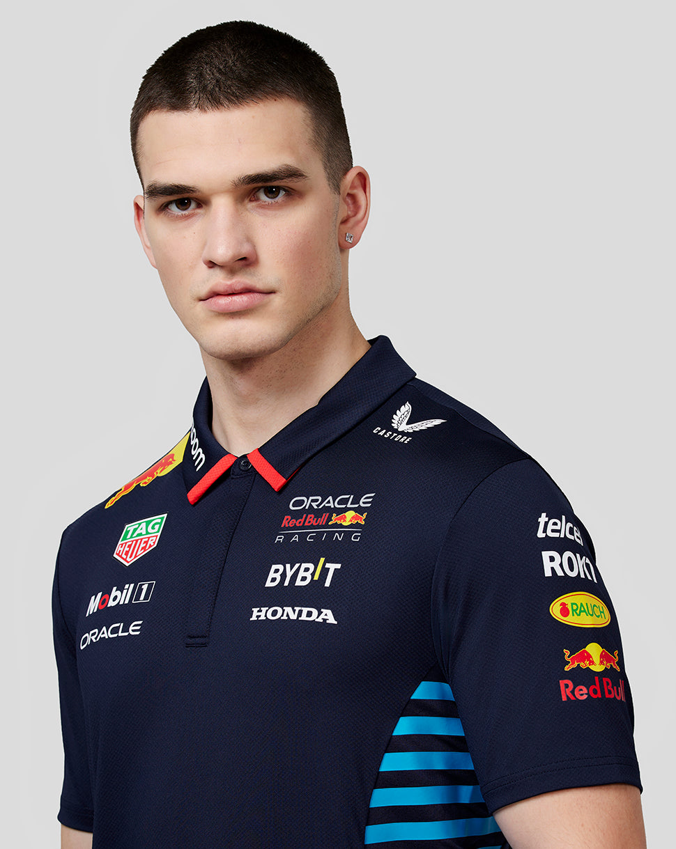 Close-up of a male model in a night sky navy Red Bull Racing polo showing front logos and fabric texture
