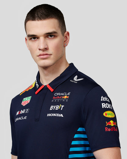 Close-up of a male model in a night sky navy Red Bull Racing polo showing front logos and fabric texture