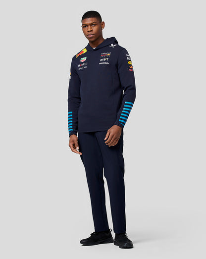 Front view of a man wearing a navy teamline hoodie with Oracle Red Bull Racing logos on the chest and blue stripe details on the sleeves
