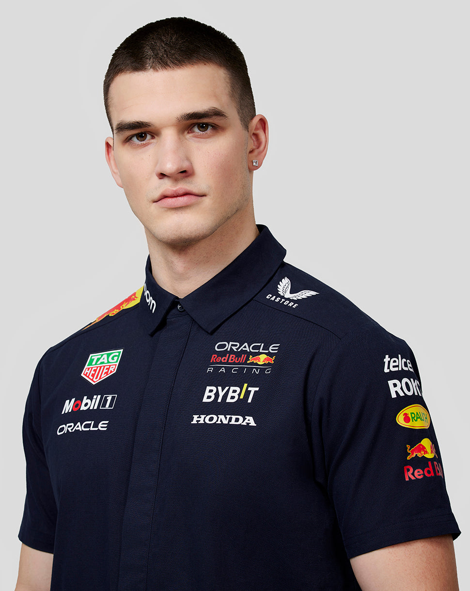 Close-up of model in navy Teamline shirt showing prominent sponsor logos on chest and shoulder