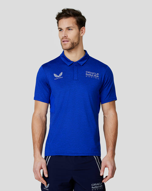 Male model wearing a blue Oracle Red Bull Racing polo with Castore wing logo on the chest