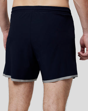 Back view of navy running shorts with elastic waistband and light grey hem trim.