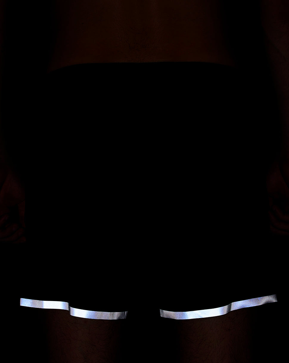 Back view of navy running shorts with reflective trim at the leg openings