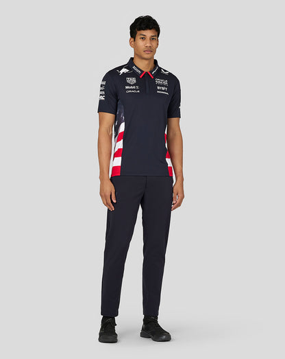 Back view of a man in a navy Night Sky Teamline polo with red white side panels and prominent sponsor graphics on the back.