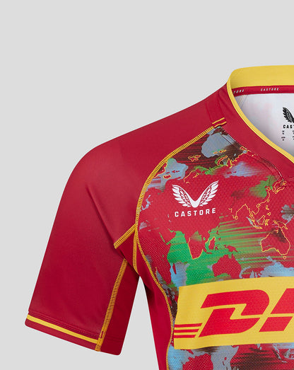 Shoulder and chest close-up of the red Harlequins shirt displaying world map print and collar branding.