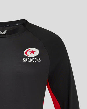 Close up of black Saracens matchday long sleeve tee showing left chest crest and right chest Castore branding with red side panel.
