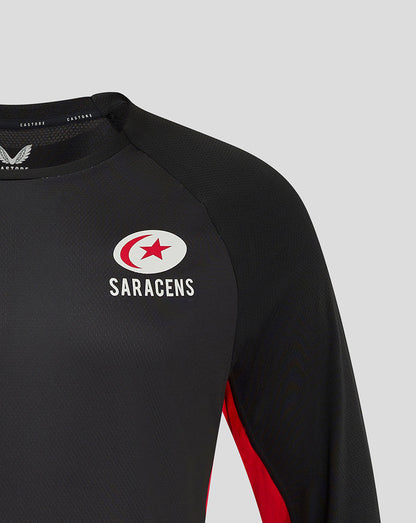 Close up of black Saracens matchday long sleeve tee showing left chest crest and right chest Castore branding with red side panel.