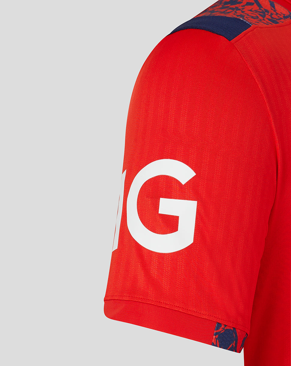 Shoulder and chest area of red England cricket shirt with navy floral shoulder trim and branding.