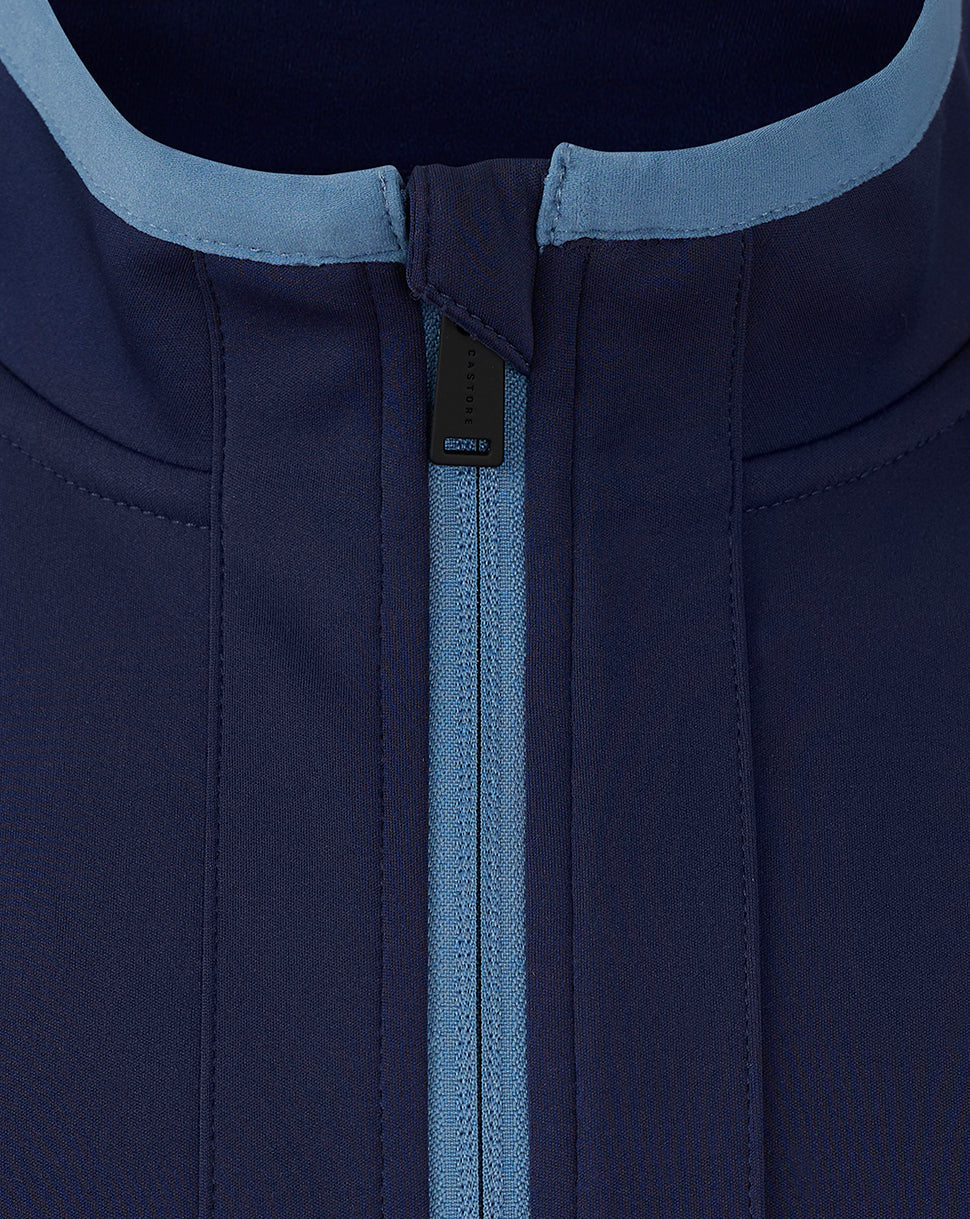 Close-up of the neck area showing light blue collar trim and center back zip detail on the navy travel jacket.
