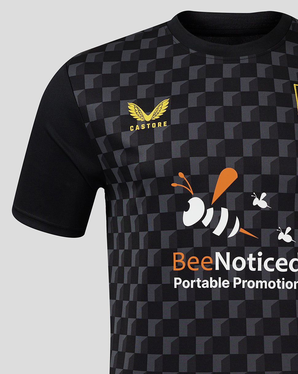 Mansfield Third Shirt close-up features crest on left chest and BeeNoticed front print against a dark geometric pattern