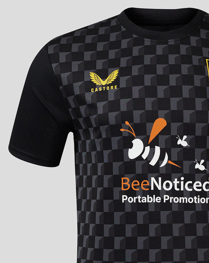 Mansfield Third Shirt close-up features crest on left chest and BeeNoticed front print against a dark geometric pattern