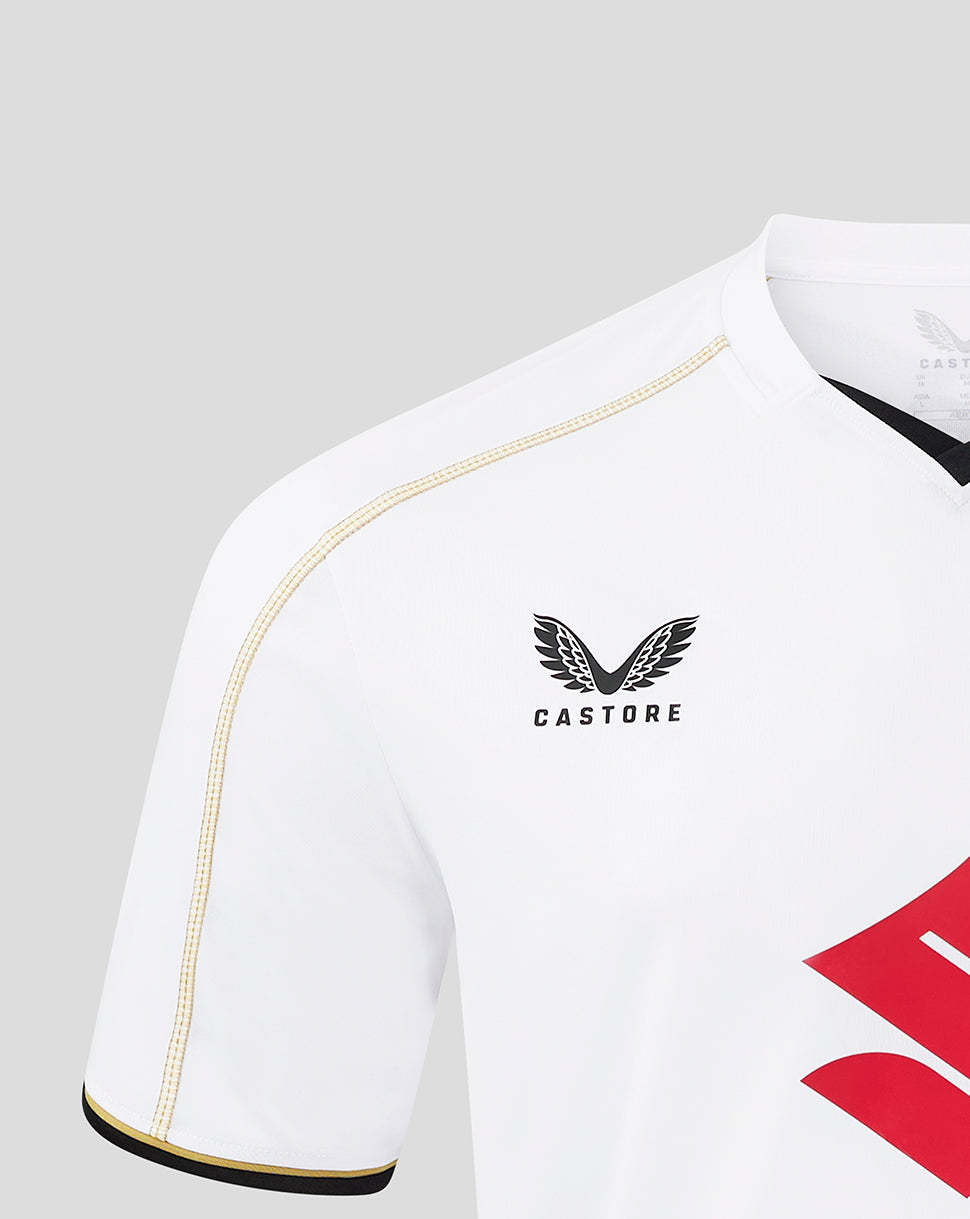 Shoulder close-up of white MK Dons home shirt showing gold piping and partial club crest