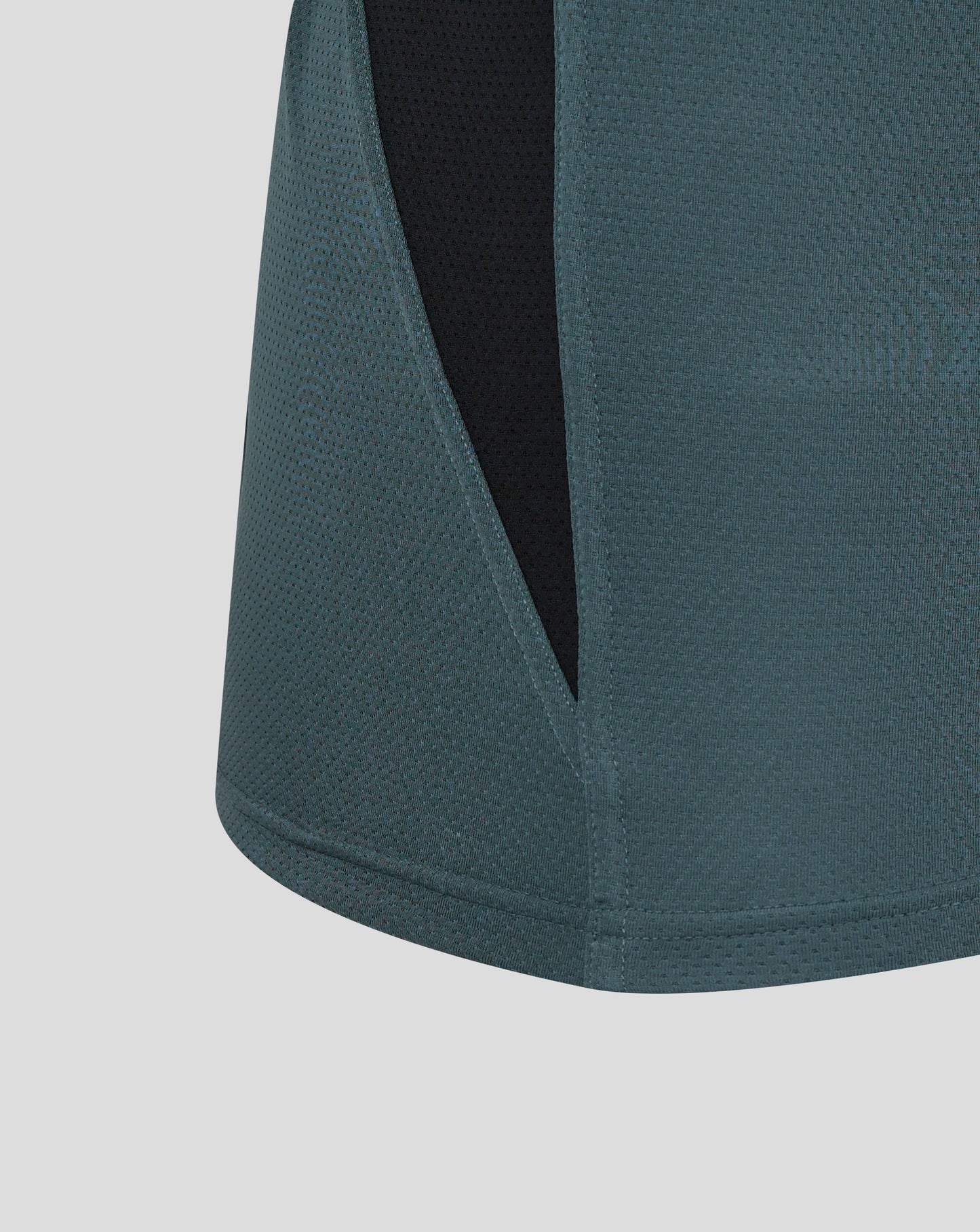 Detail of Bath Rugby training vest fabric showing teal panels with a black side panel and a curved hem